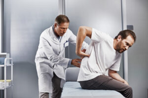Doctor is examining male patient with back pain