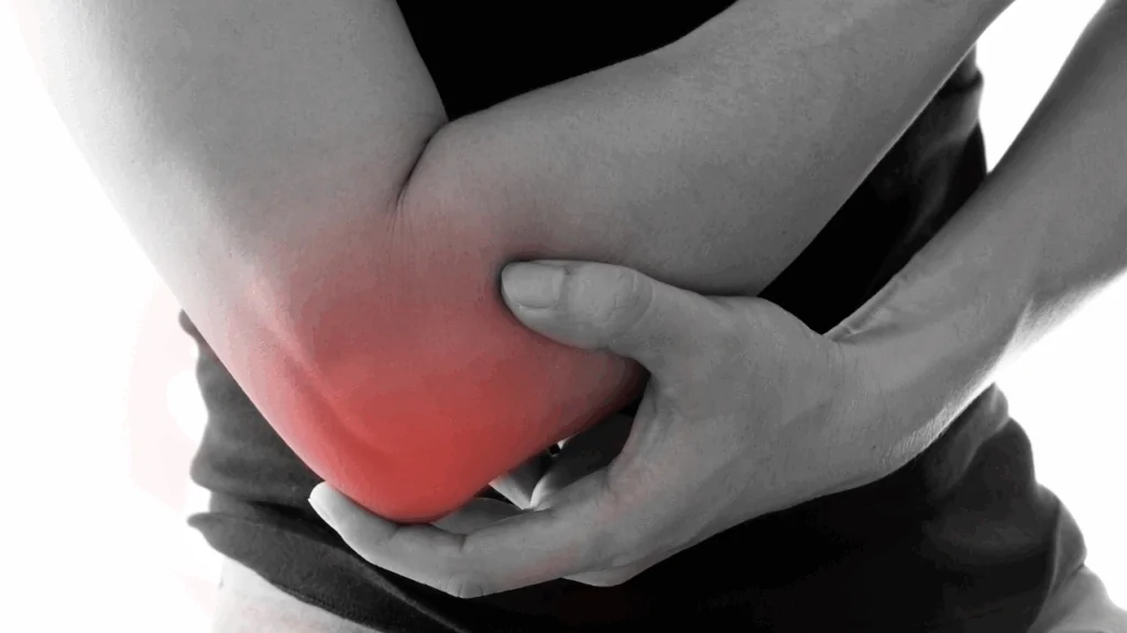 A grayscale close-up of a person clutching a painful, red-highlighted elbow to demonstrate the symptoms requiring tennis elbow treatment from a chiropractor in Fort Lauderdale.