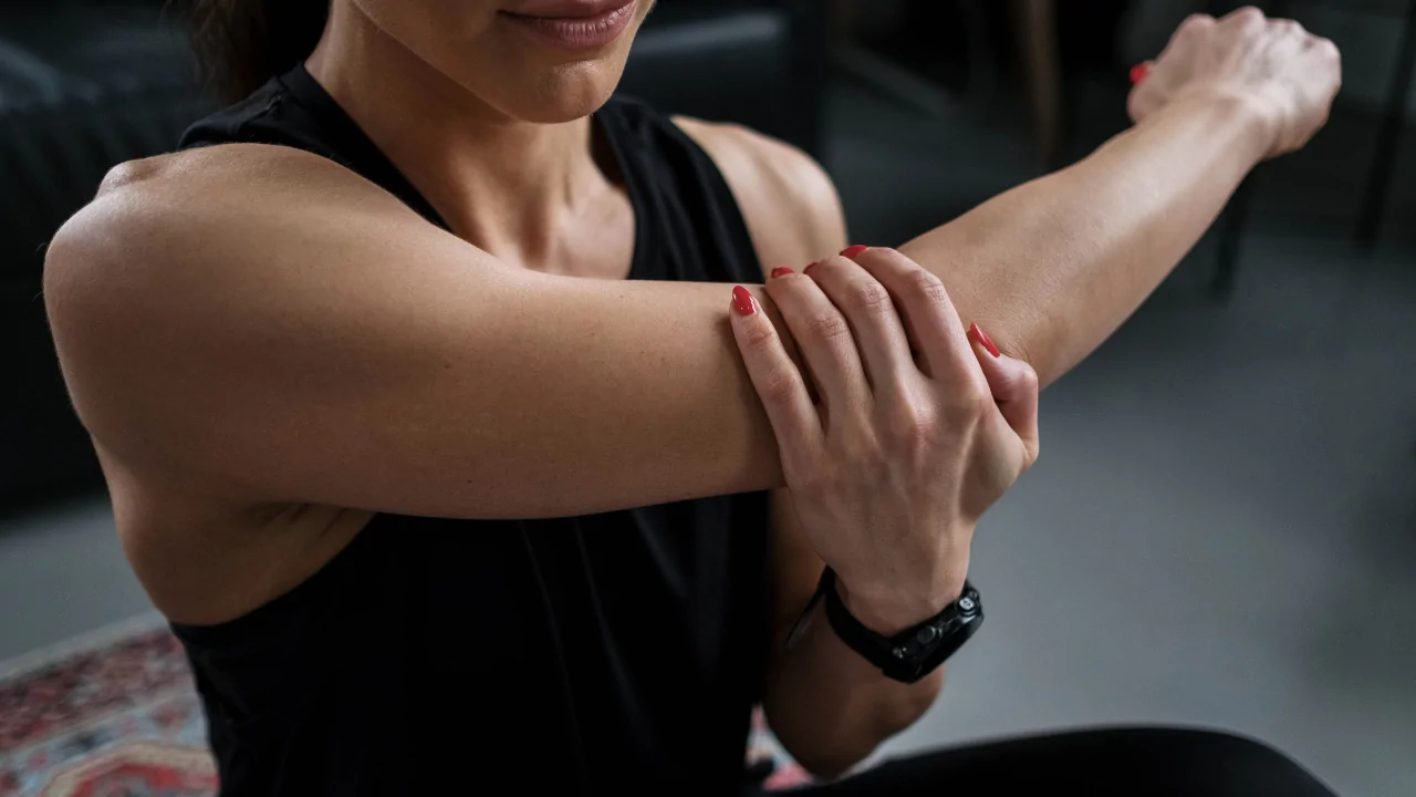 A male clinician in a grey shirt performing a manual forearm and elbow adjustment on a female patient to provide tennis elbow treatment in Fort Lauderdale.