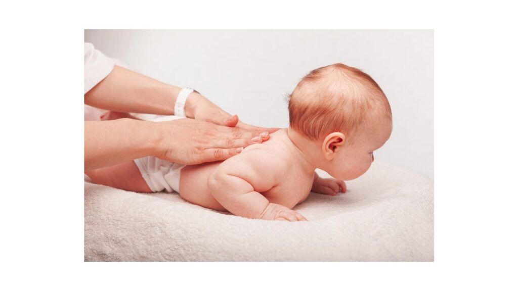 A chiropractor in a white medical tunic performing a light-pressure spinal assessment on an infant to represent specialized infant chiropractic care at Spine and Joint Center in Fort Lauderdale.