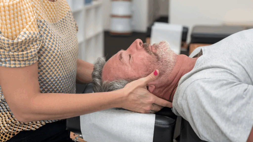 A healthcare professional performing a gentle manual neck adjustment on a patient to provide chiropractic-led physical therapy at Spine and Joint Center in Fort Lauderdale.