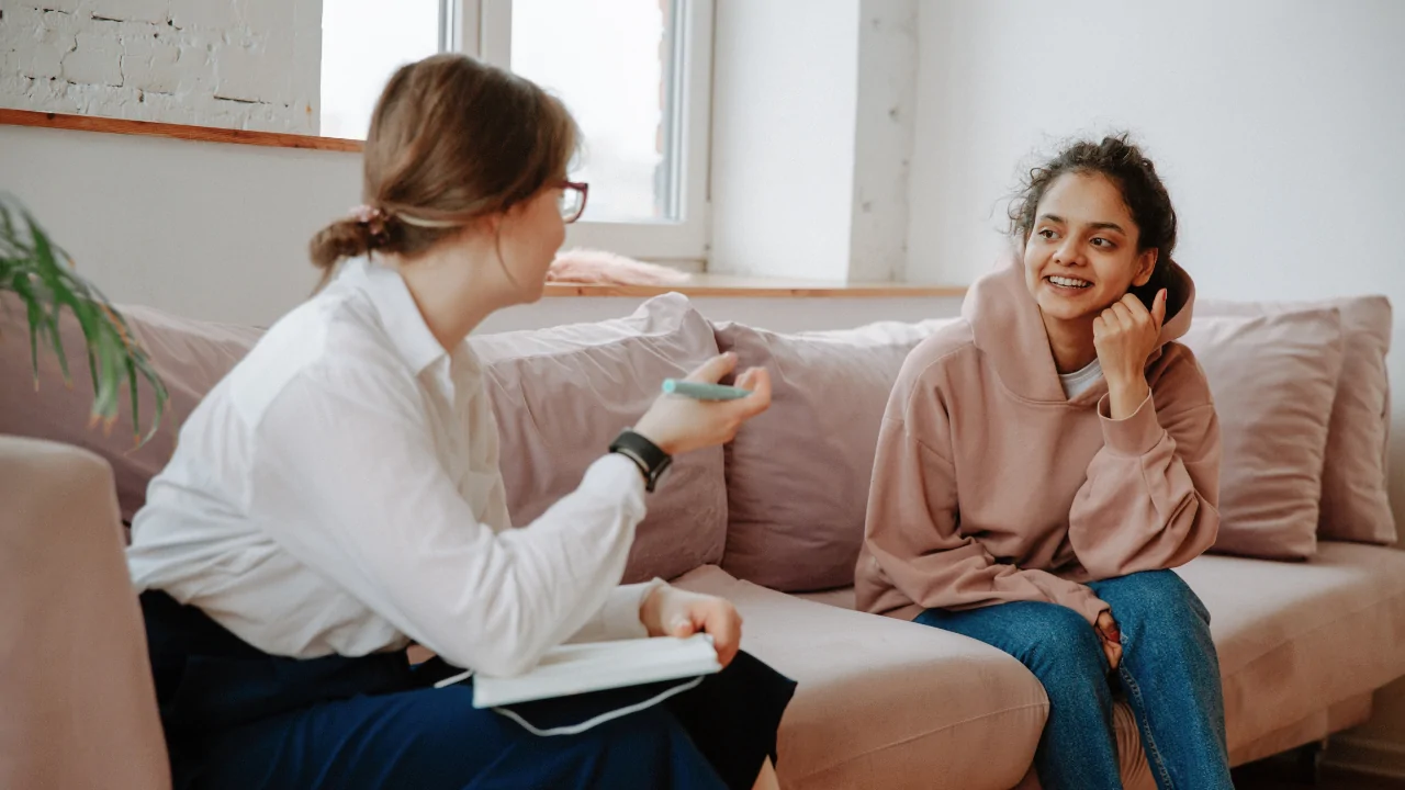 A counselor sitting on a couch and speaking with a young woman to provide personalized chiropractic nutritional counseling in Fort Lauderdale.