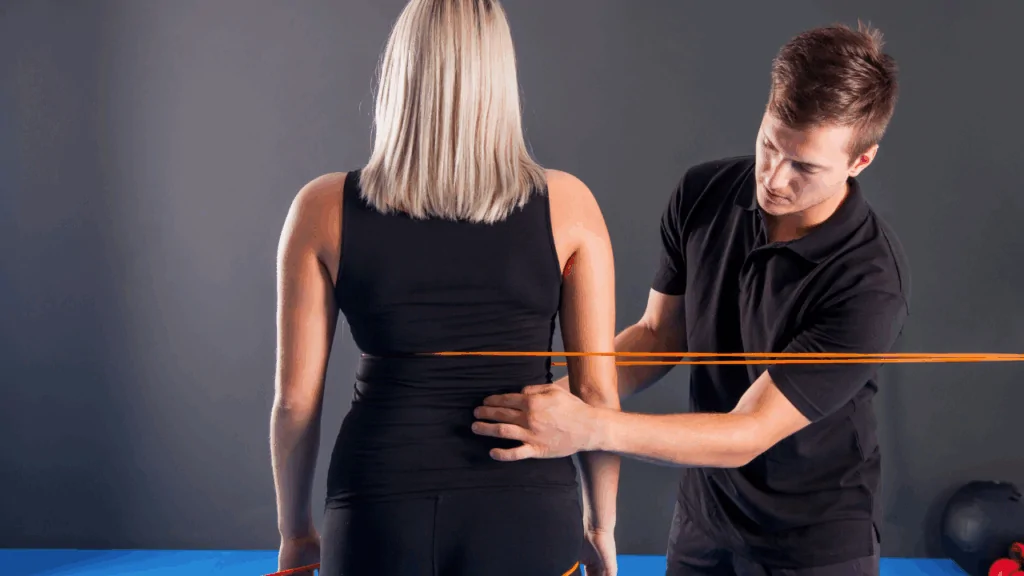 A chiropractor conducting a chiropractic postural assessment on a patient using orange level lines to identify spinal alignment at Spine and Joint Center in Fort Lauderdale.