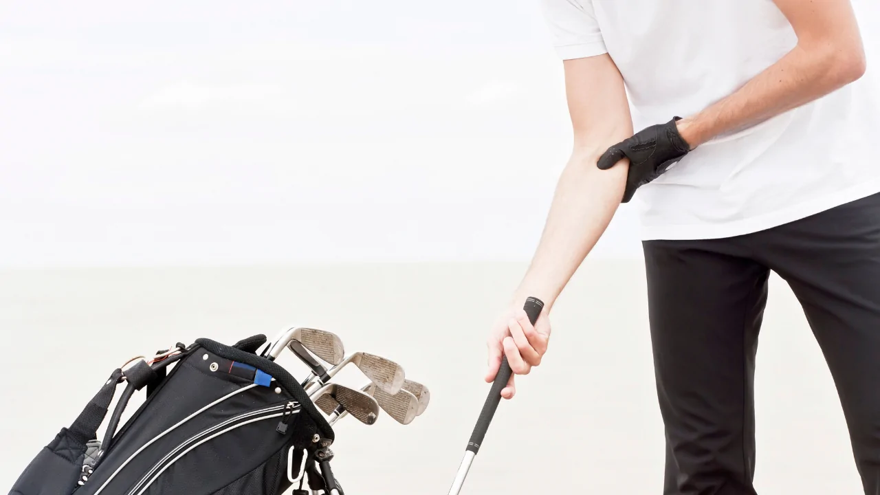 A close-up of a golfer holding a club with a black support brace on their forearm to manage symptoms while seeking chiropractic treatment for golfer’s elbow in Fort Lauderdale.
