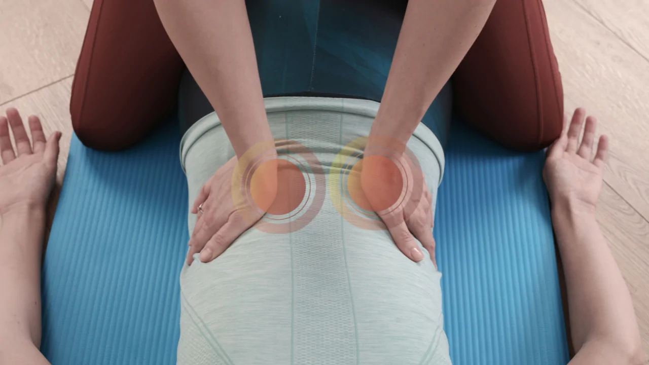 A close-up of a chiropractor’s hands performing a bilateral lower back palpation with highlighted circular indicators to represent the targeted growing pains treatment provided at Spine and Joint Center in Fort Lauderdale.