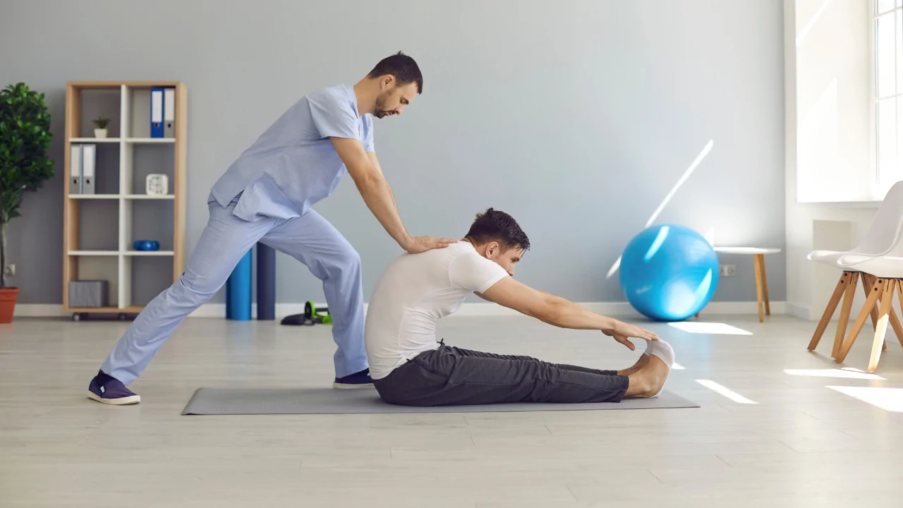 Chiropractor guiding a patient through a seated back-stretch exercise in Fort Lauderdale