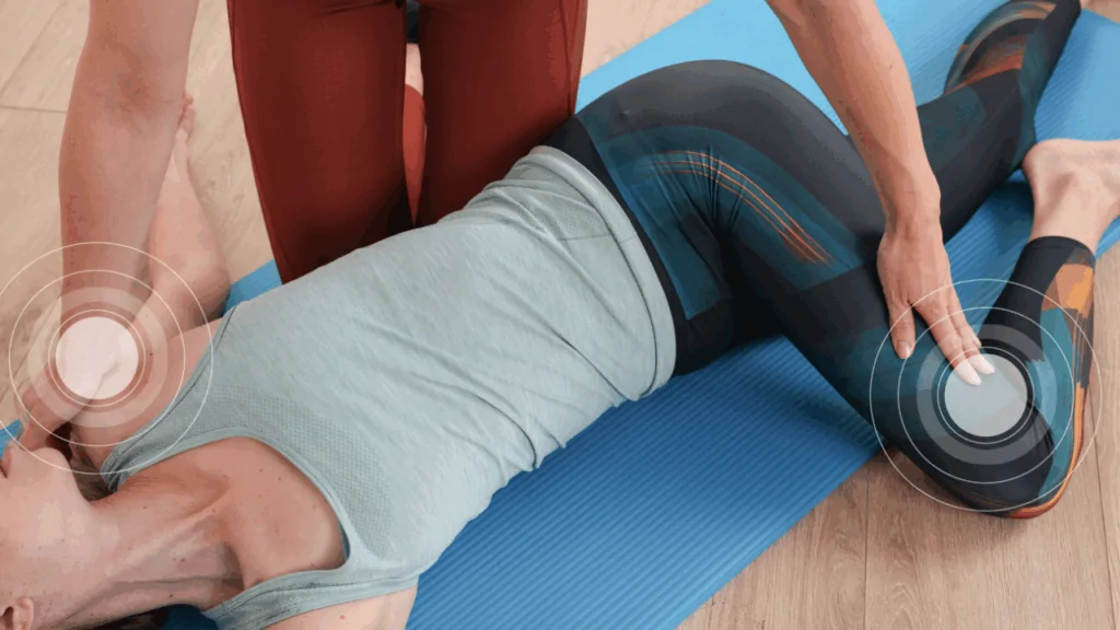 A woman in athletic wear lying on a blue mat while a provider performs a manual adjustment on her hip and shoulder, with concentric circle overlays highlighting pain points to represent the targeted hip pain chiropractic care at Spine and Joint Center in Fort Lauderdale.