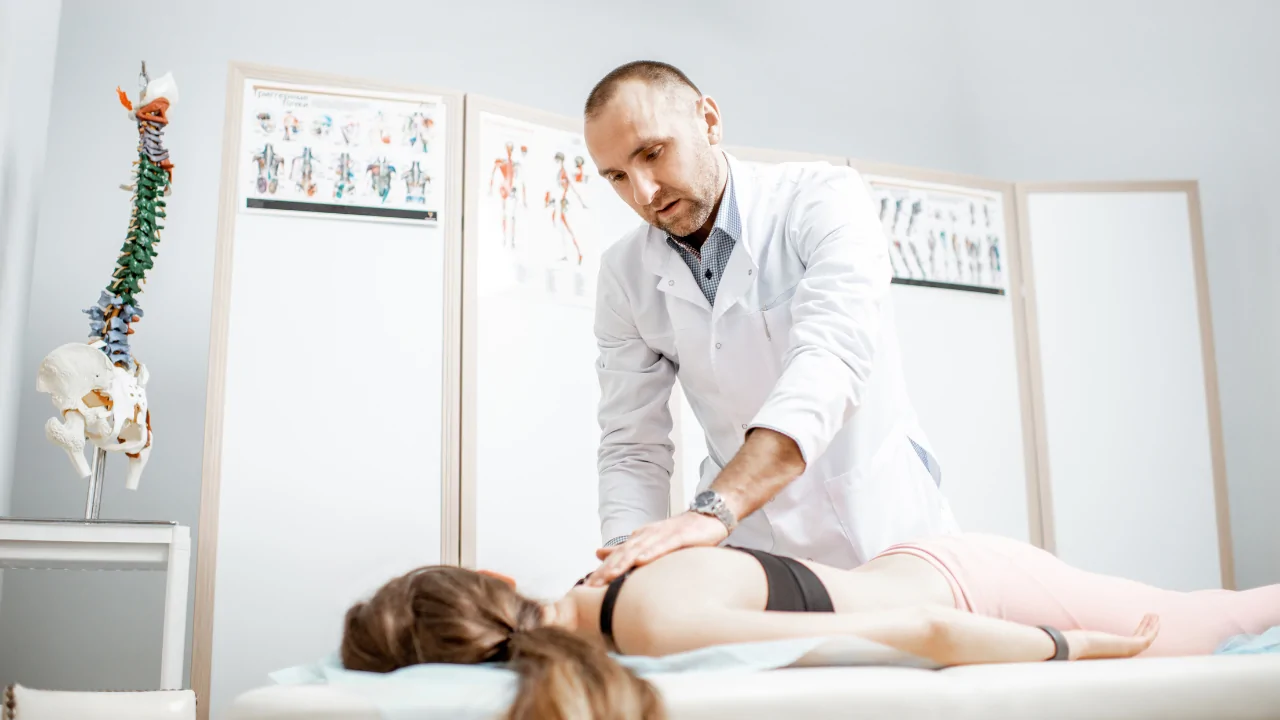 A clinician in a white coat performing a focused spinal adjustment on a female patient to provide osteoporosis management at Spine and Joint Center in Fort Lauderdale.