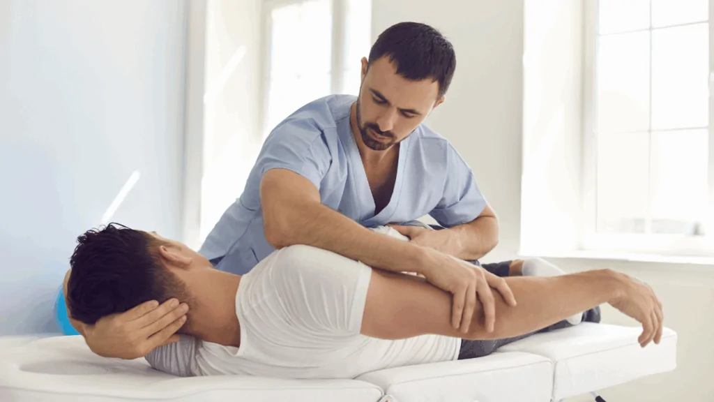 A chiropractor in blue scrubs performing a manual spinal adjustment on a male athlete to provide specialized care as a weightlifting chiropractor in Fort Lauderdale, FL.