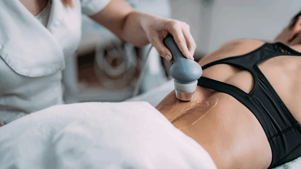 A healthcare professional in a blue medical tunic using a handheld ultrasound wand on a patient’s lower back to provide chiropractic ultrasound therapy at Spine and Joint Center in Fort Lauderdale.