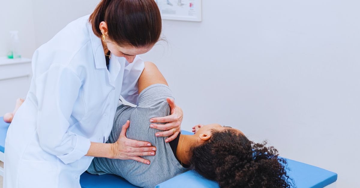 A chiropractor in a white clinical coat performing a gentle shoulder mobilization technique on a patient to provide frozen shoulder treatment at Spine and Joint Center in Fort Lauderdale.
