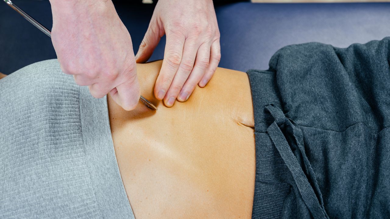 A clinician using a precision Graston tool to treat a patient's flank and lower back area, aimed at breaking down fascial restrictions in Fort Lauderdale.