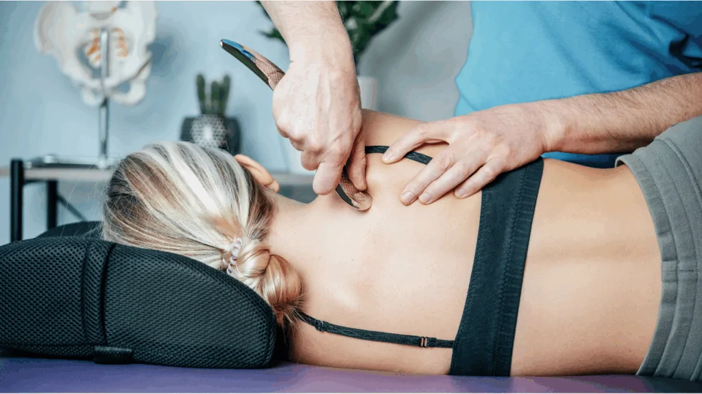 A clinician in a white medical coat performing Myofascial Release Therapy on a patient's upper back and neck to improve mobility in Fort Lauderdale.