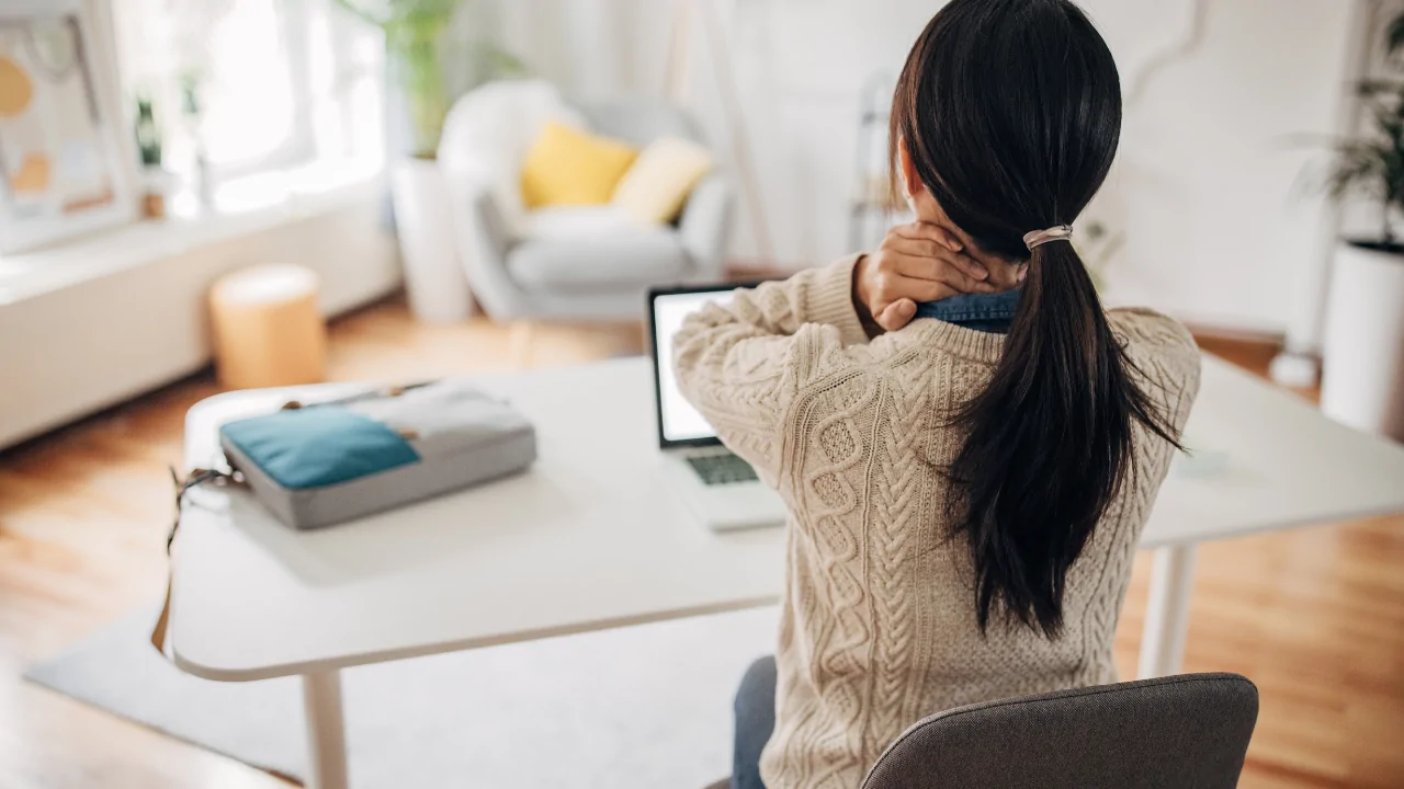 A chiropractor in a blue medical tunic performing a manual cervical spine adjustment on a woman to provide tech neck treatment at Spine and Joint Center in Fort Lauderdale.